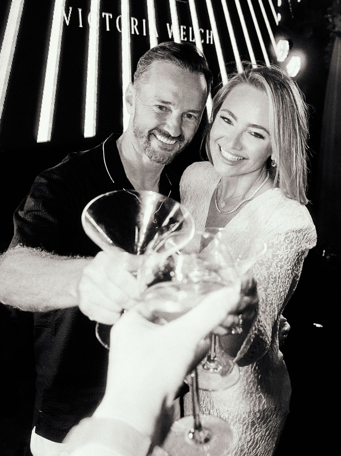 Michael and Victoria Welch, founders of IYKYK, raising a glass at a private event